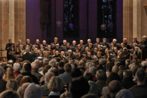 A choir performs in a dimly lit church for an audience.