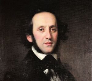 A formal portrait of a man with curly hair and sideburns, wearing a dark suit with a high white collar. He gazes directly at the viewer, set against a dark background.