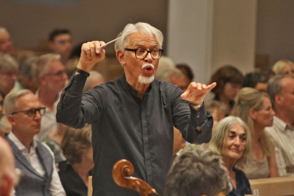 A conductor passionately directs a musical performance in front of an attentive audience.